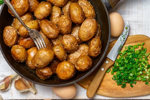 油炸土豆放在油锅里 大蒜和青葱 鸡蛋和盐 生食和熟食 乡村风味 背景是白色木板 — 图库照片