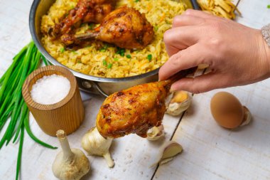 Bir kadının eli kızarmış tavuk etini kızarmış lahana, sarımsak ve yeşil soğan, peynir, çiftlik yumurtası ve tuzla dolu bir tavaya koyar. Beyaz ahşap bir tahtanın üzerinde kırsal bir tarzda yemek pişirir.