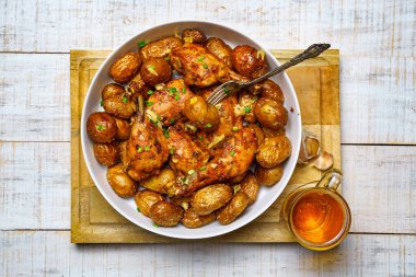 Kırsal tarzda lezzetli bir öğle yemeği, sağlıklı yiyecekler - bir bardak bira, kızarmış tavuk eti ve soyulmamış kızarmış patates, doğranmış pırasa, beyaz ahşap bir tahtanın üzerinde pişmiş yemek.