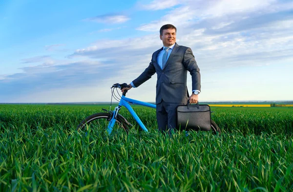 ビジネスマンは緑の芝生の上に自転車で立って遠くを見て ビジネススーツを着て ブリーフケースと書類 春の美しい自然 ビジネスコンセプト — ストック写真