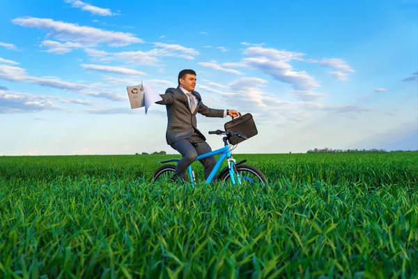 ビジネススーツを着たビジネスマンが緑の草原を自転車で走り ブリーフケースと書類 春の美しい自然 ビジネスコンセプト — ストック写真