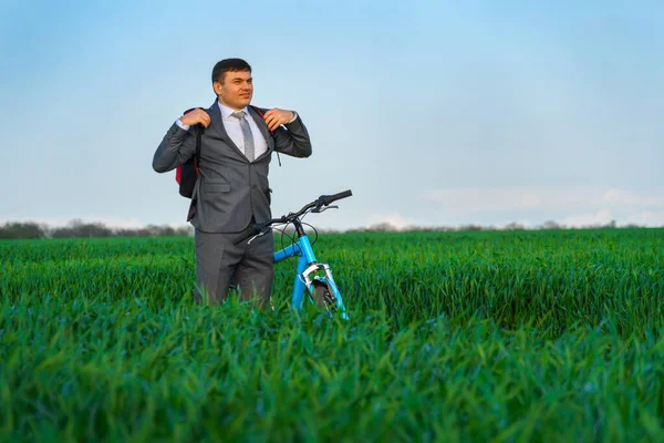 ビジネスマンはバックパックに自転車で緑の草原にポーズビジネススーツに身を包んだ春の美しい自然ビジネスコンセプト — ストック写真