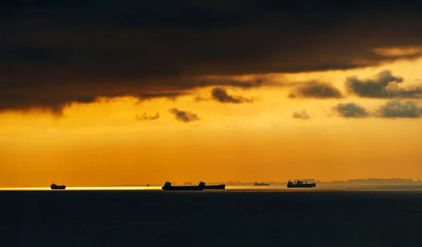 하늘을 배경으로 바다에 배들의 실루엣 파도에서 반사된 스톡 사진