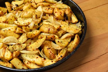 Kızartma tavasında kızarmış patates, pişmiş yemek, lezzetli kabuk, ahşap arka planda bir nesne.