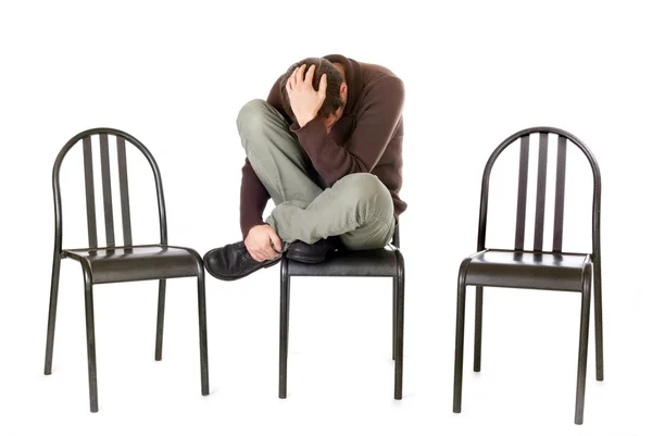 Sám a smutný muž sedí na židli, izolované na bílém — Stock fotografie