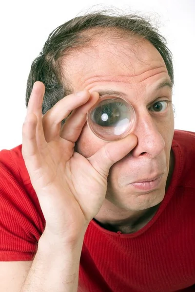 Мужчина держит увеличительную линзу на правом глазу и смотрит в камеру — стоковое фото