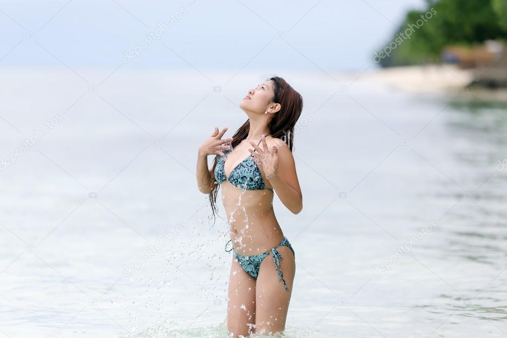 Young woman in a bikini splashing in the sea