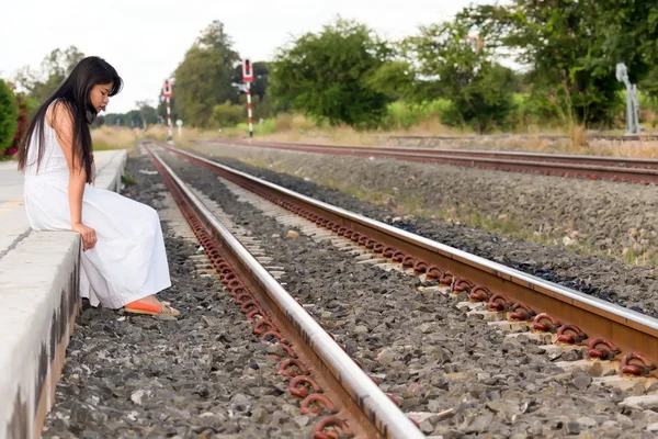 Jovem mulher sentada em uma plataforma de trem rural — Fotografia de Stock