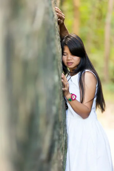 Young Thai girl holding onto a rock — Stock Photo, Image