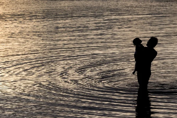 Père et fils dans la mer silhouette au coucher du soleil — Photo