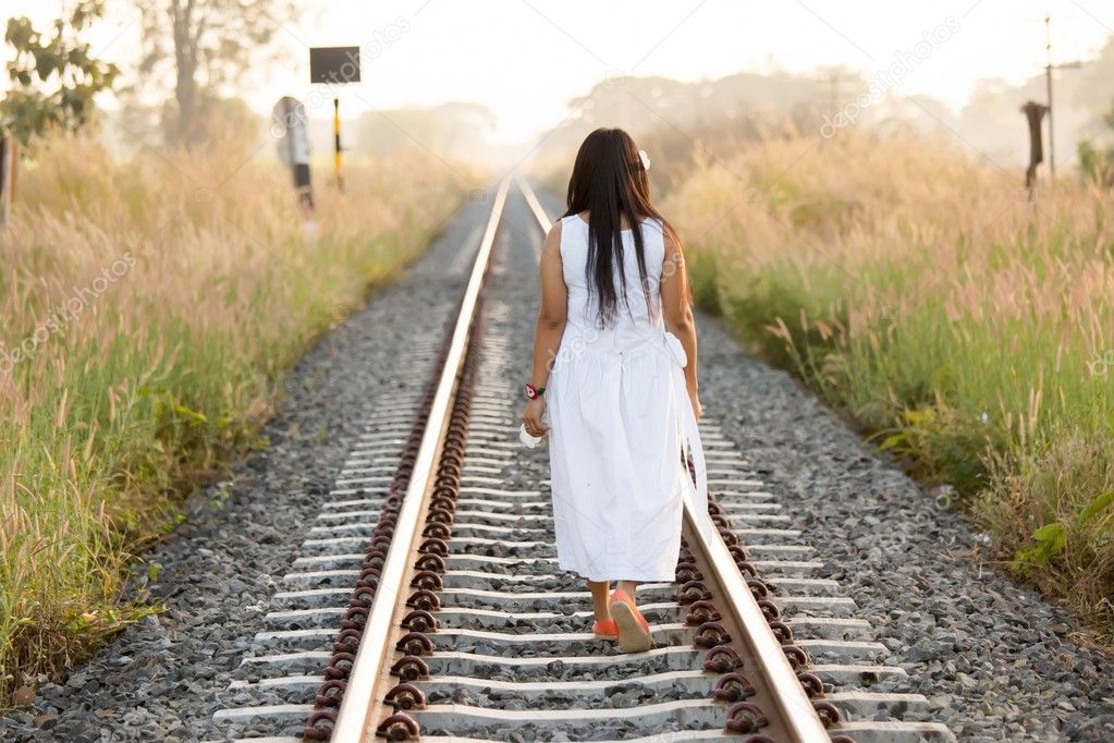 Young woman walking down a railway track