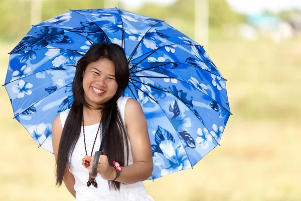 Prachtige Thaise meisje onder een blauwe zonnescherm — Stockfoto