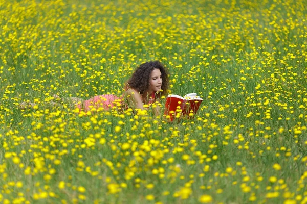かわいい若い女性読んで横たわっている巻き毛を持つ — ストック写真