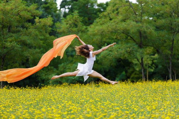 Agile woman leaping in the air trailing a scarf