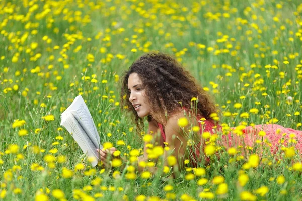 かわいい若い女性読んで横たわっている巻き毛を持つ — ストック写真