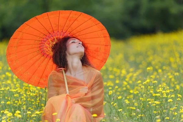 Schöne elegante Frau mit einem orangefarbenen Regenschirm — Stockfoto