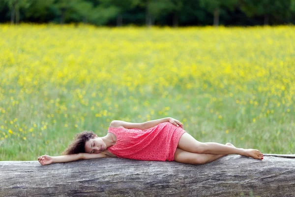 Vacker ung kvinna som sover på en stock — Stockfoto
