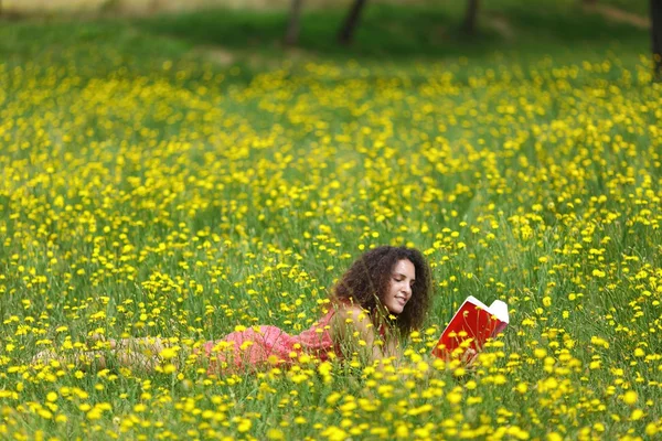 Jeune femme mignonne avec des cheveux bouclés couché lecture — Photo