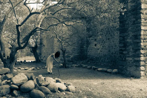 古いキリスト教礼拝堂の近くに放棄されたツイストオリーブの森のプランテーションを歩く顔のない幽霊アジアの女性 — ストック写真