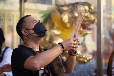 BANGKOK, THAILAND - 03 January 2022 : A man holding incense sticks is praying in the Tiger god shrine for new year 2022 during the coronavirus pandemic .