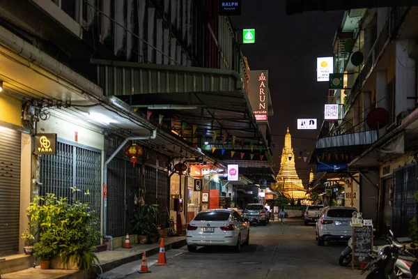 BANGKOK, THAILAND - 10 DECEMBER 2021 : View on the Wat Arun ancient Buddhist temple from a deserted street at night.