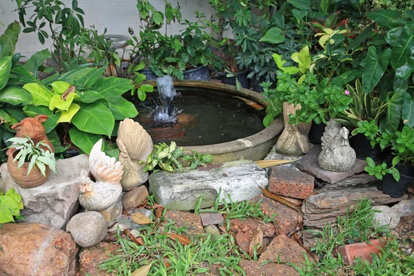 Kip en varken beelden bij aardewerk fontein in tuin — Stockfoto