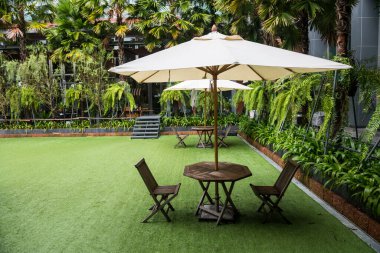 Sandalyelerin içindeki beyaz şemsiye ve oteldeki muhteşem bahçe..