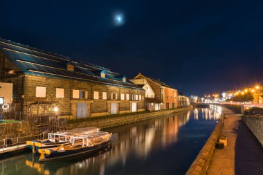Tarihi Otaru kanalı, turist tekneleri ve geceleri gökyüzü yansıması ve Japonya 'nın parlayan ayı olan eski bir yapı deposu. Hokkaido 'daki ünlü seyahat merkezi..