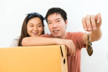 Yeni taşınma evinin çift anahtarı. Karton kutudan eşyaları çıkarıyorlar. Evde yeni bir çift hayatı kurarız. Emlak alımı.