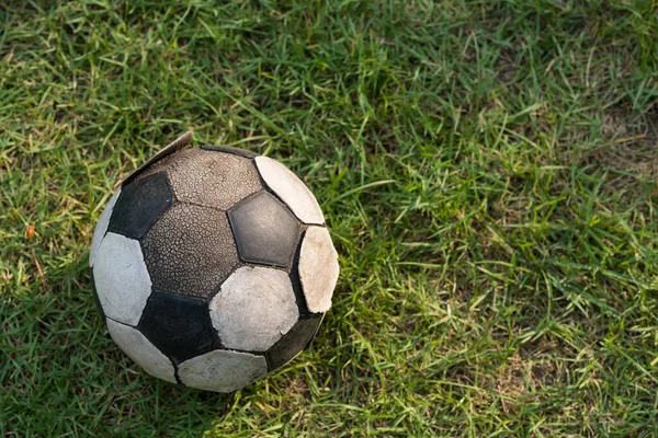 旧足球放在绿草上 顶部有自然光和阴影 Grunge在恶劣的情况下扭伤了足球的皮肤 — 图库照片