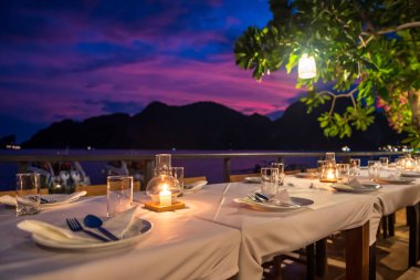 candle lamp on table with Phi Phi Don seascape and twilight sky at dusk, Krabi, Thailand. Famous travel destination or holiday maker of Siam. Romantic family or group dinner.