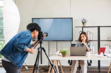 Sahne arkası konsepti. Videograf, genç Asyalı blog yazarı stüdyoda ışıklandırmayı canlı yayınlamadan önce görüntüleri kaydetmeye hazır olun. Yayın vlogger, internet etkileyiciName.