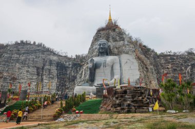 Poeple vitis Stone Buddha heykeli U Thong, Suphanburi, Tayland 'daki Wat Khao Tham Thiam' da dağlarla çevrili..