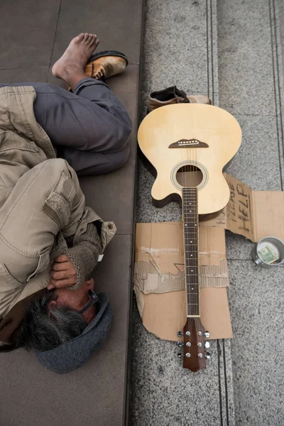 ギターで街の階段で寝ている老人やホームレスの男性のトップビュー 寄付のボウルにお金 ヘルプテキストと段ボール 悪天候の冬は寒さを感じ — ストック写真