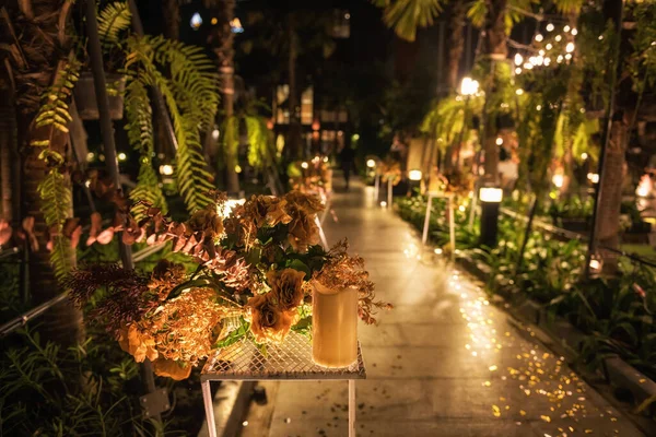 在灯火通明的美丽花园举行的户外婚礼上 假金花装饰花束 — 图库照片