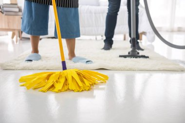 Halıda sarı paspas ve elektrikli süpürge ve beyaz yatak odasında yer. Hafta sonları birkaç rutin ev temizliği ya da hijyen.