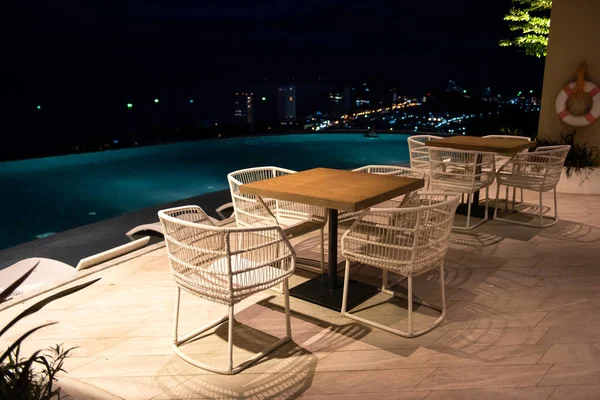 酒店屋顶游泳池在夜间与模糊的城市景观背景 游泳池边的放松座位 — 图库照片