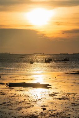 Silhouette wooden boats on beach shore at sunset at Bang Phra beach, Srirachai, Chonburi province , Thailand. Fisherman local port. Vertical landscape.
