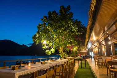 Akşam yemeği masası, Phi Phi Don 'un alacakaranlıkta yediği yemek masası, Tayland, Krabi' de aydınlatılmış bir dekorasyon. Yaz tatili ya da tropikal ülkede tatilci, Siyam.