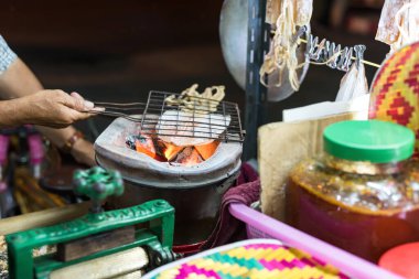 Dried squid grilled on a charcoal stove. Thai famous street food in Hua Hin night market.