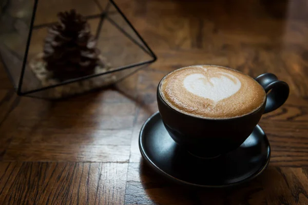 ミルクハートのホットラテアートコーヒーは カフェで松のトウモロコシの装飾と木製テーブルの上にペイント — ストック写真