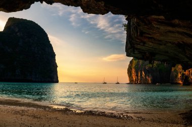 Maya sahilindeki taş kemer mağarası gün batımında Krabi, Tayland 'daki Koh Phi adası yakınlarında. Ünlü tatil beldesi ya da tropikal ülke Siyam 'da yaz tatilcisi