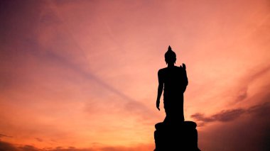 Silhouette standing buddha statue against twilight sky at dusk in Phutthamonthon Buddhist park, Bangkok, Thailand.
