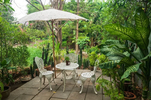 White table and chairs set with parasol in outdoor cafes or restaurant, tea table set in garden