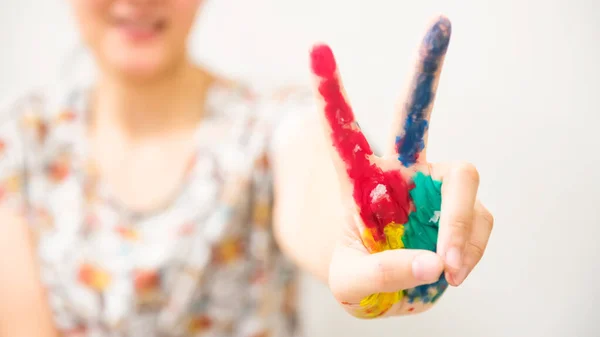 colorful paint hand with victory gesture of smiling Asian woman isolated on white background. Art work concept.