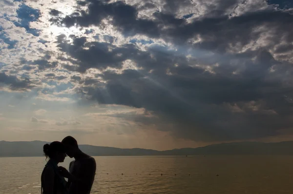 Pareja compartiendo el amor en la playa durante el hermoso atardecer Imágenes de stock libres de derechos