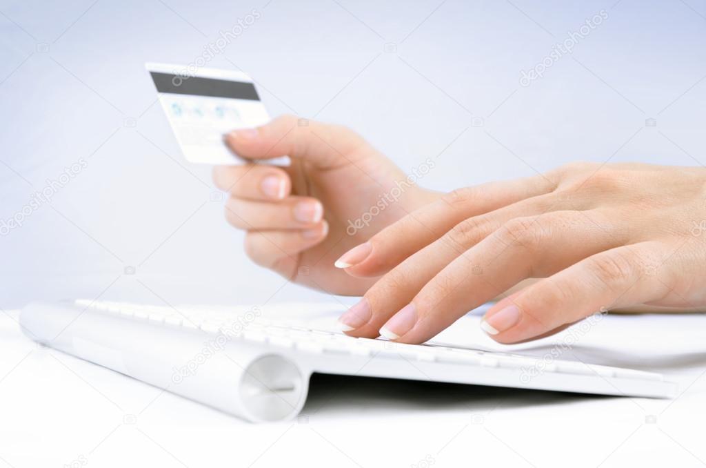 Woman's hands holding a credit card and using computer keyboard for online shopping