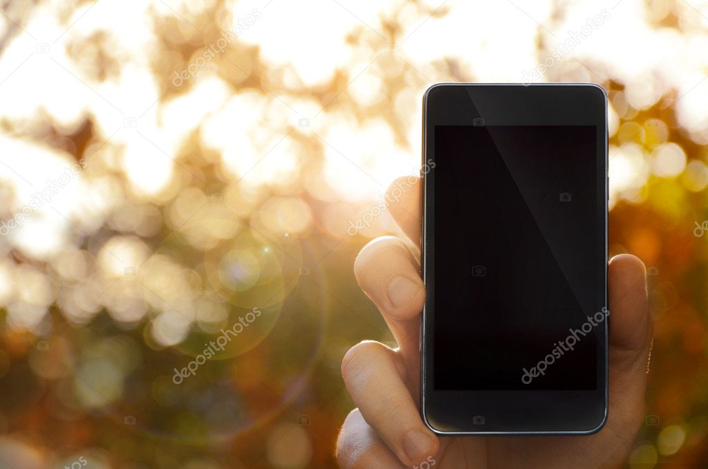 Hand holding smart phone, blurred background