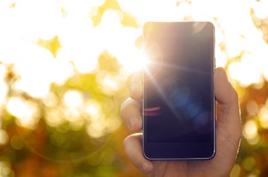 akıllı telefon bulanık doğa arka planda tutan adamın elini