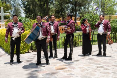 TLACOLULA, OAXACA, MEXICO - 23 Mayıs 2022: Parroquia Santa Maria de la Asuncion 'un dışında güneşli bir günde Meksika, Tlacolula' da bekleyen mariachi üyeleri